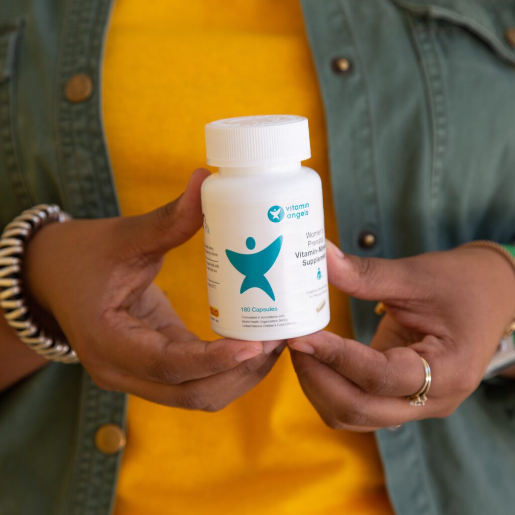 Close up of hands holding a Vitamin Angels bottle.