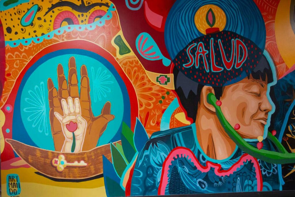 A mural depicting a group of hands, a person and the word “salud.”