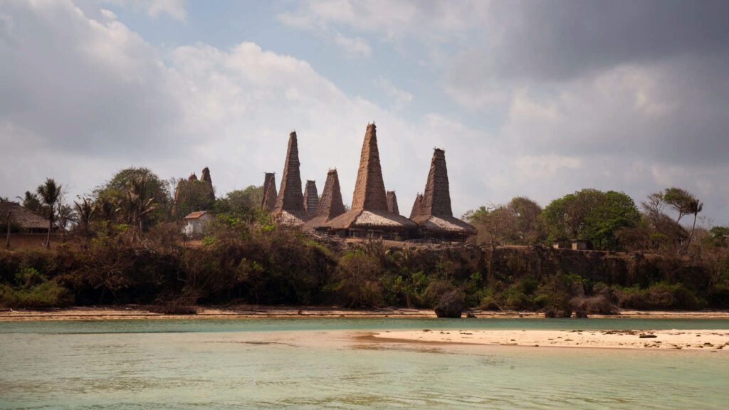 A landscape of homes with pointed tops near the ocean in Sumba, Indonesia.