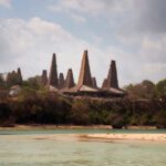 A landscape of homes with pointed tops near the ocean in Sumba, Indonesia.