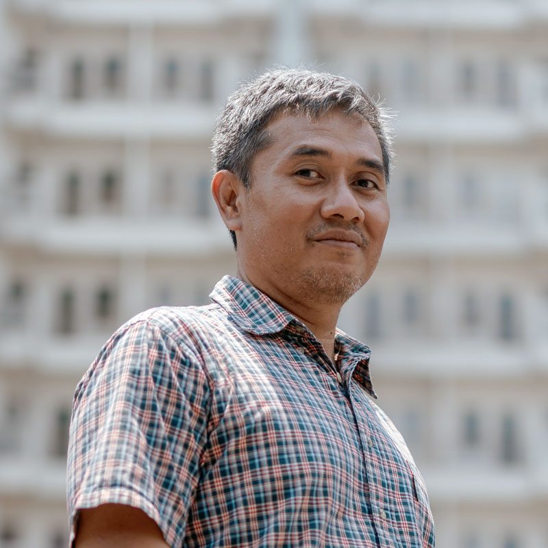 A man stands in front of a building.