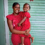 A mother and daughter outside their home wearing matching outfits.