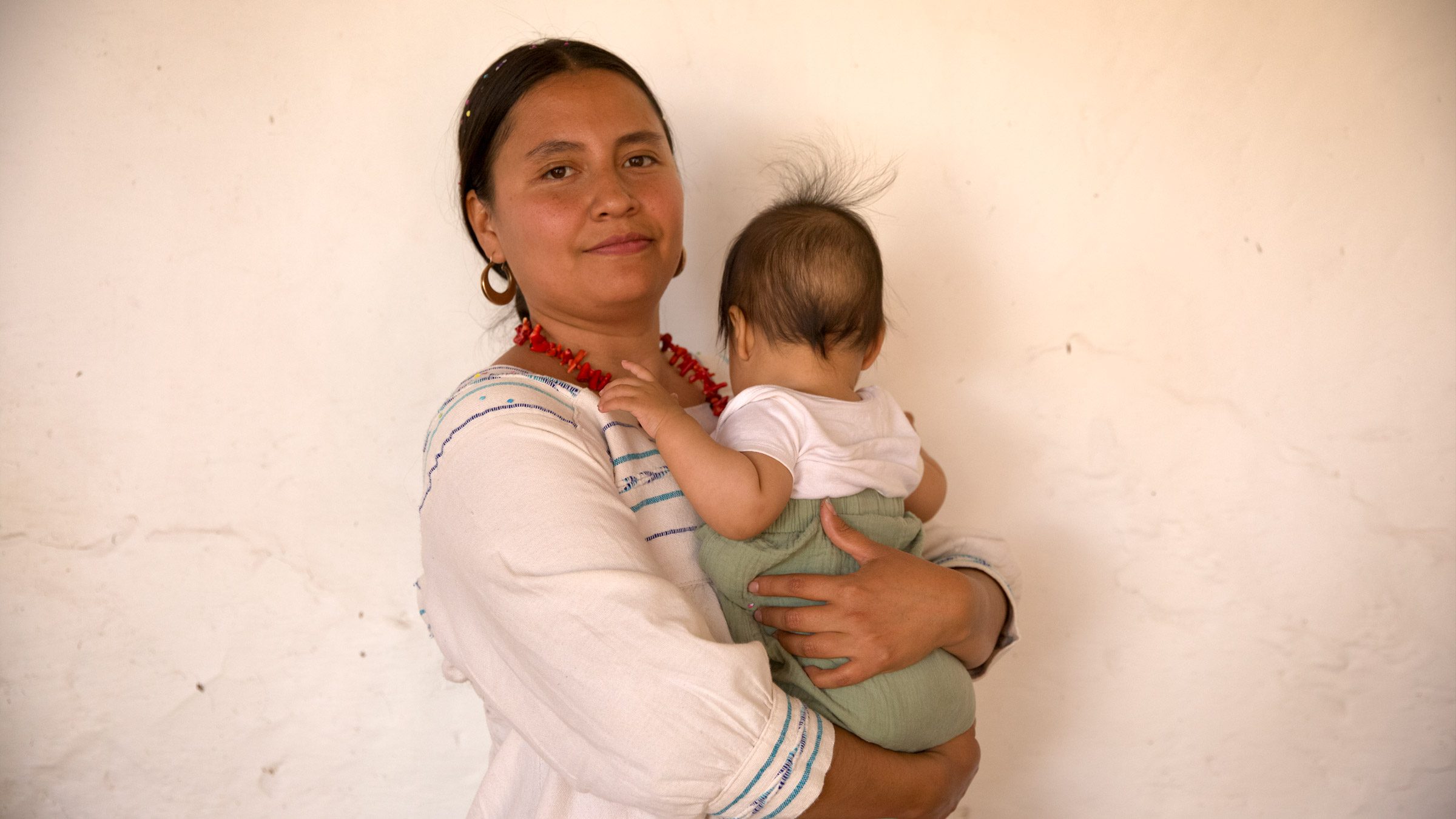 A young woman holds her baby. 
