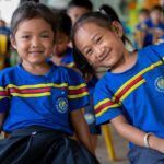 Two primary school students smile at the camera in Cambodia