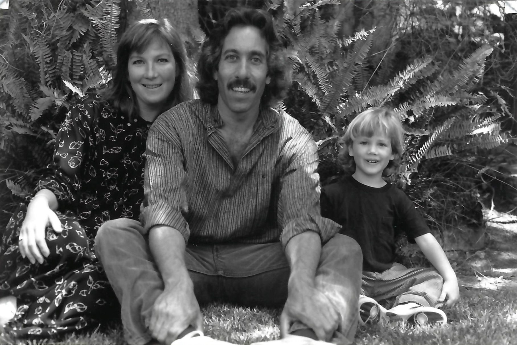 A black and white image of Howard Schiffer sitting with his wife and young son.