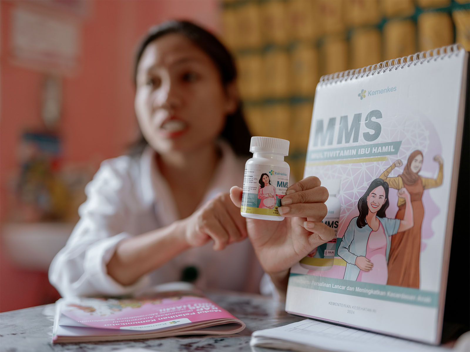A woman holds a bottle of prenatal multivitamins in India.