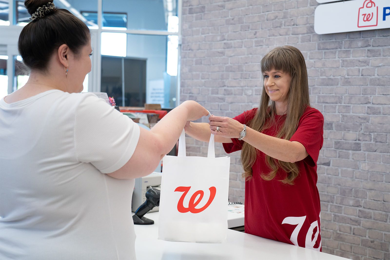 Smiling Walgreens employee hands a bag to a customer in Arizona.
