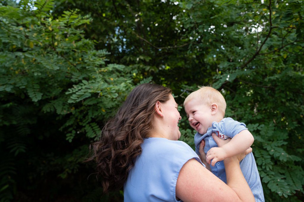 Beth lifts her son Wally into the air as they laugh together.